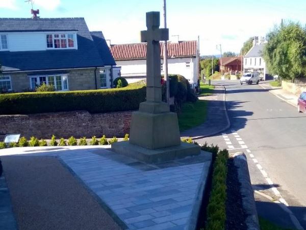 War memorial in small village after refurbishment with shrubs and overgrown grass removed