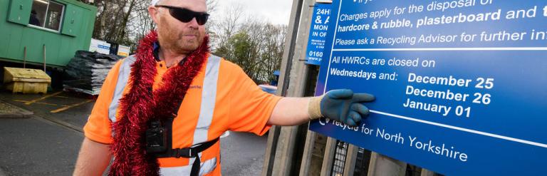 A HWRC worker pointing at the HWRC opening hours