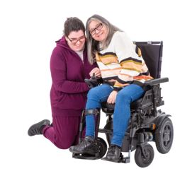 A person in a wheelchair and a lady kneeling next to them.