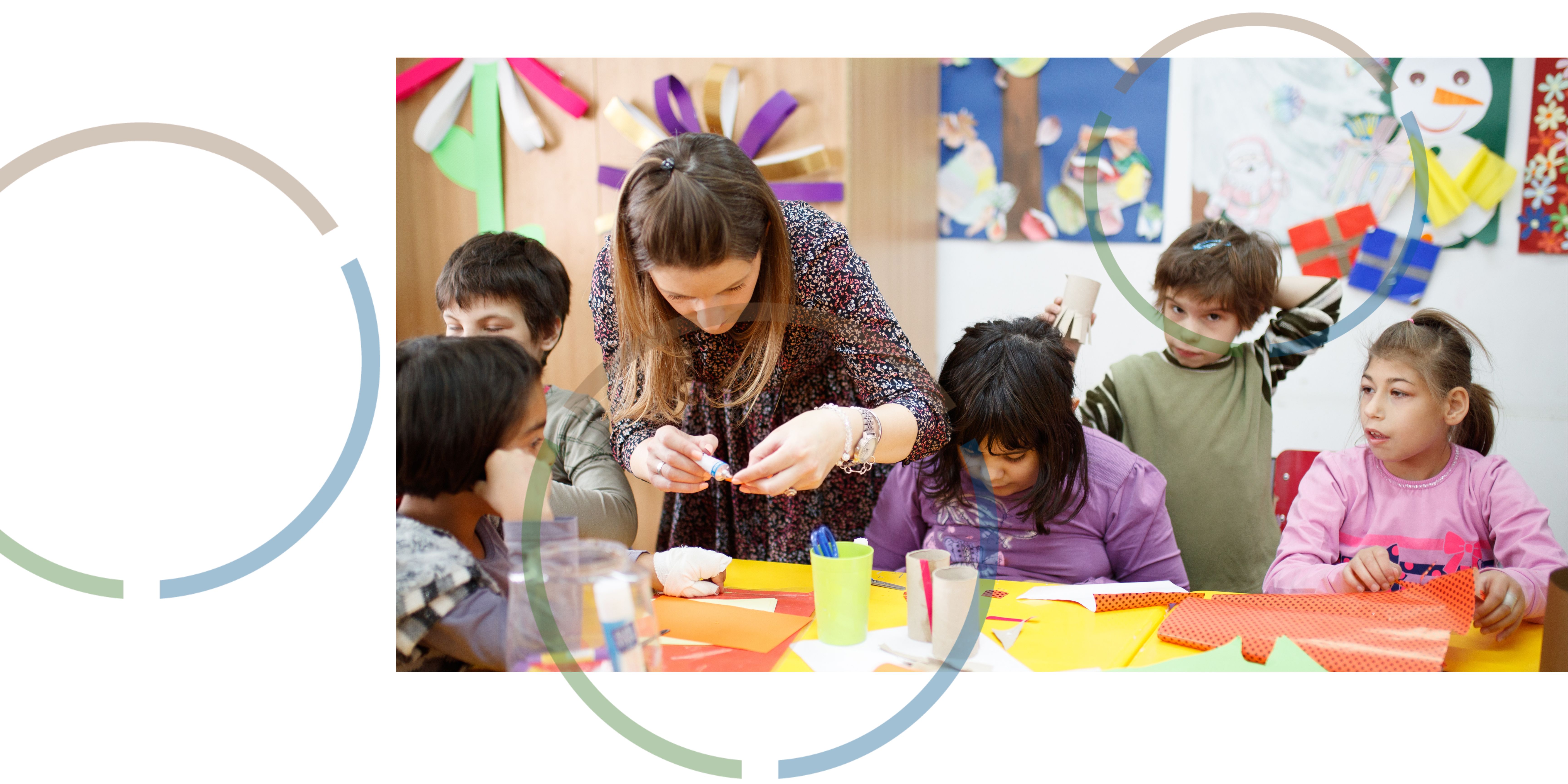 A woman helping children glue paper decorations together.