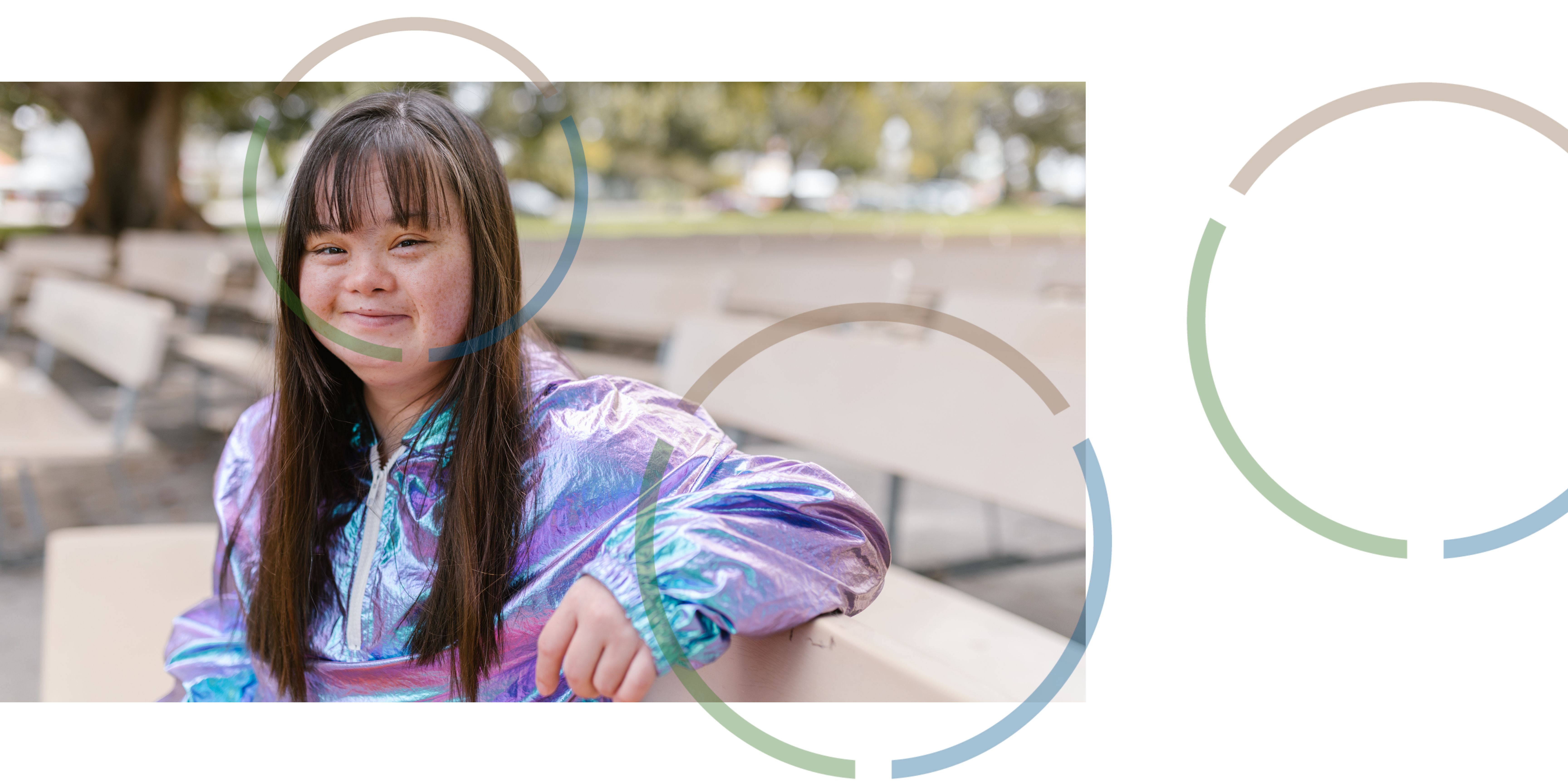 A girl smiling on a bench.