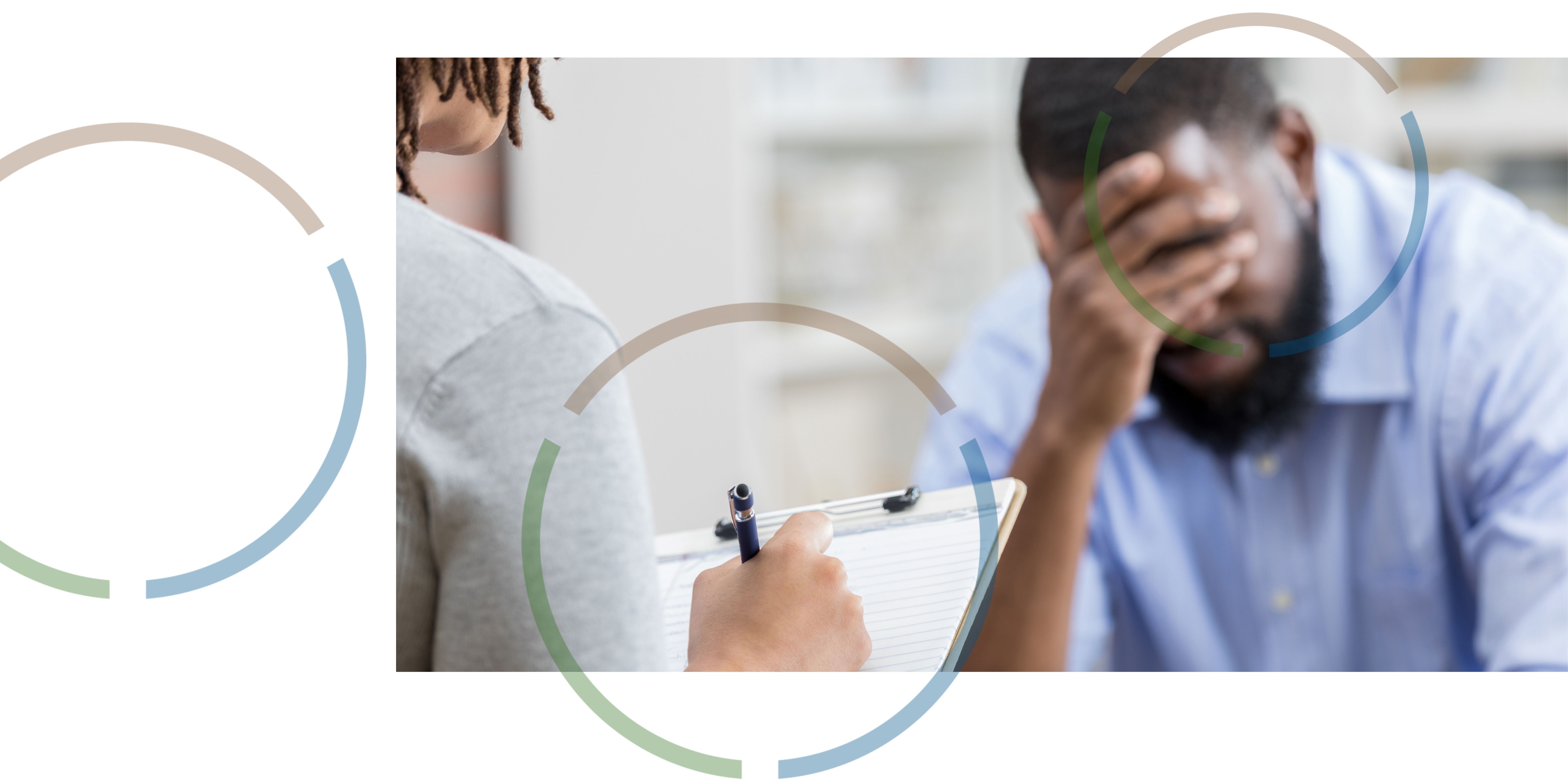 A man holding his hand in front of his face and speaking to a mental health worker.