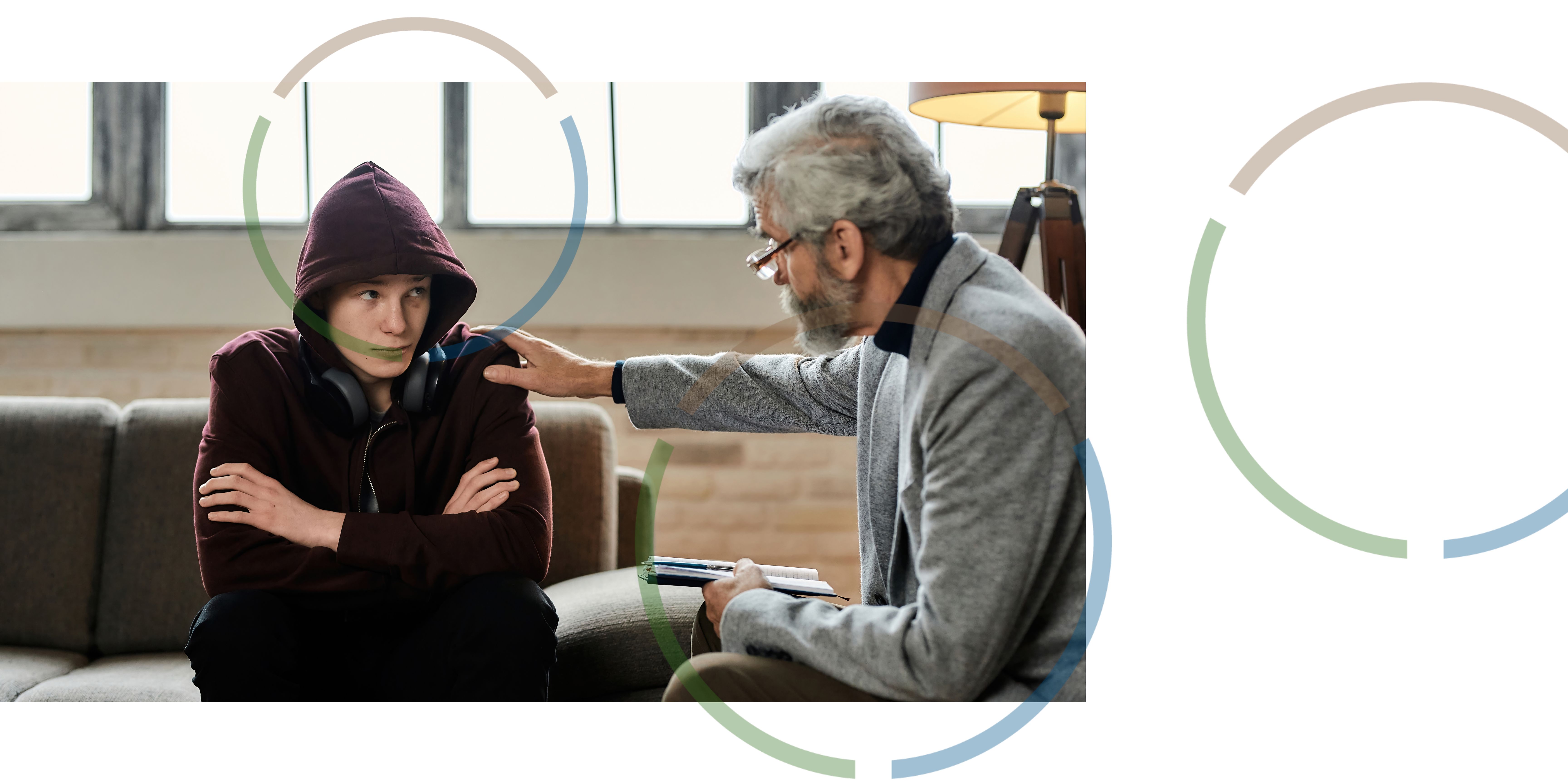 A man talking to a teenager in an office.