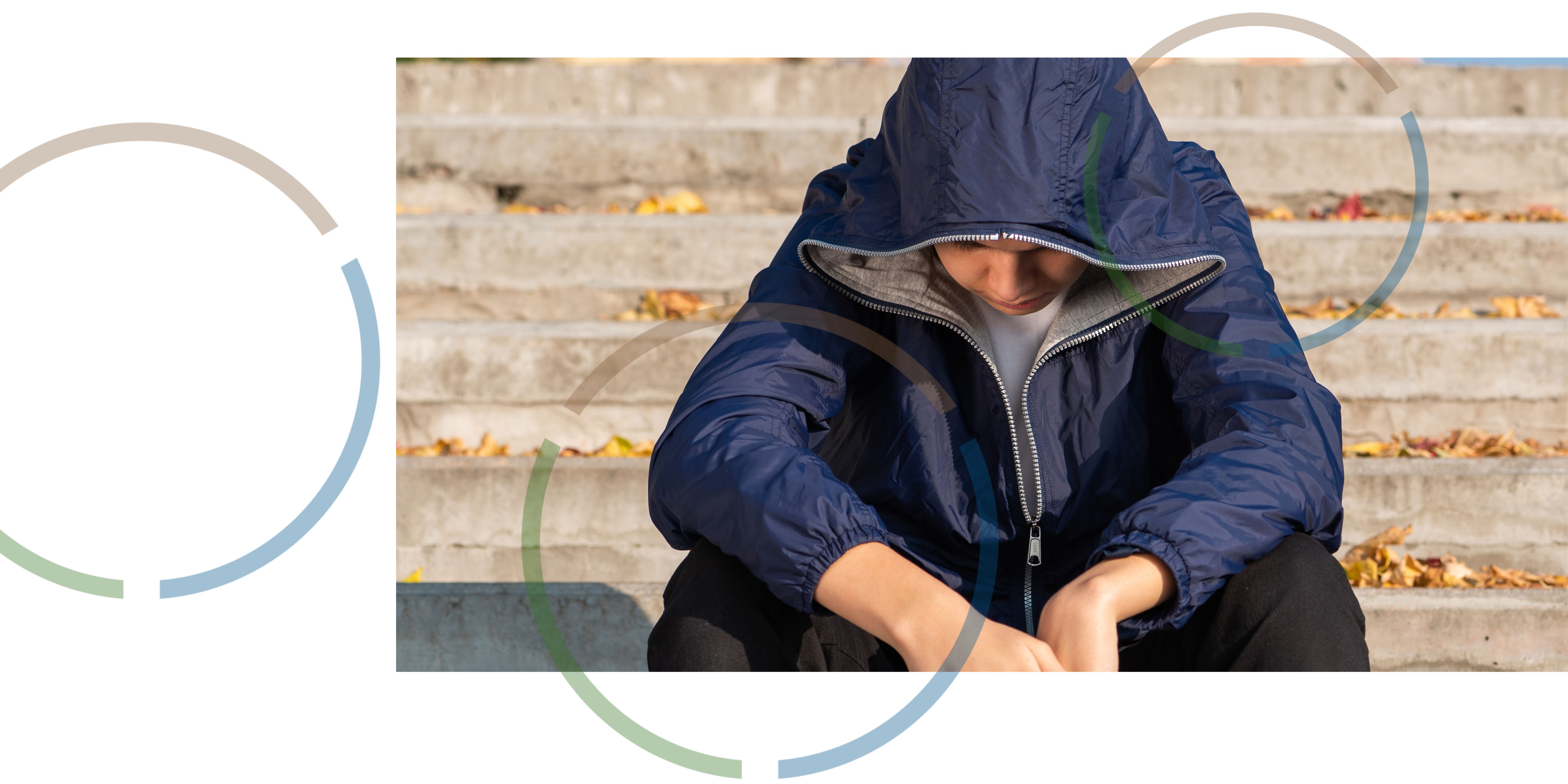 A teenager sitting on steps outside.