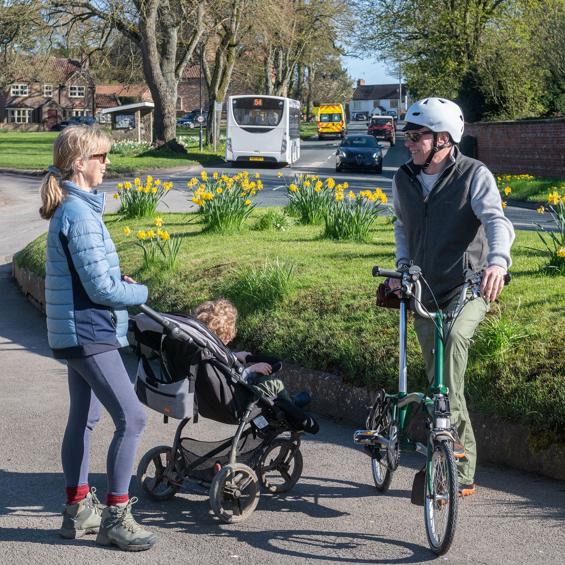 A lady with a buggy stood with a man holding a bike