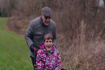 A man pushing a woman in a wheelchair. 