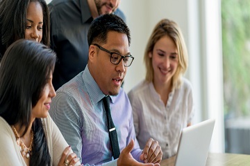 Co-workers looking at a laptop screen together.