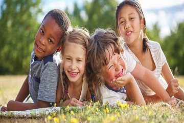 Children lying on the grass and smiling. 
