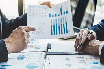 Hands pointing to graphs on a piece of paper.