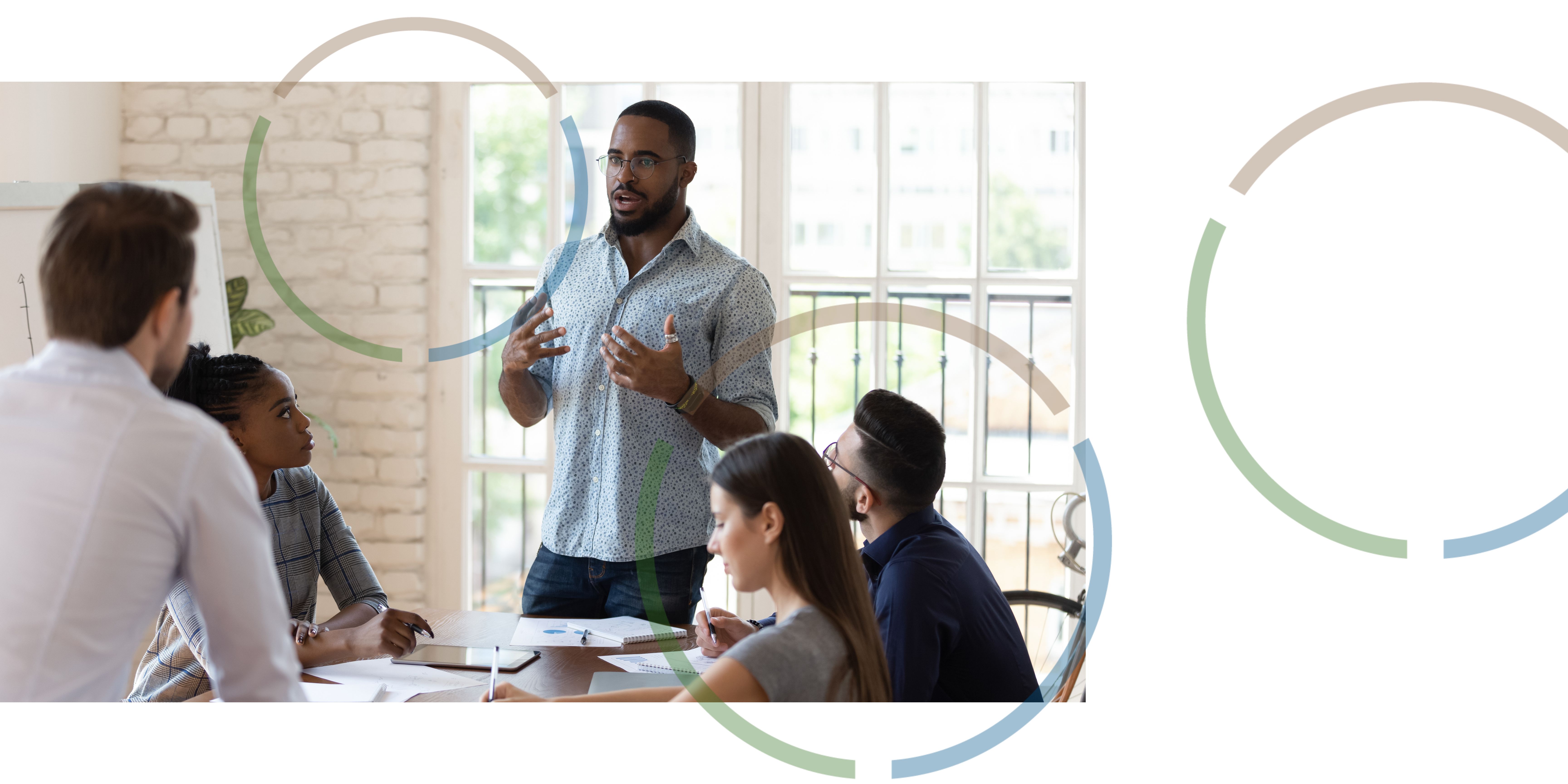 A man presenting to his co-workers in a bright office.