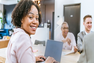 A woman smiling in a meeting with her co-workers. 