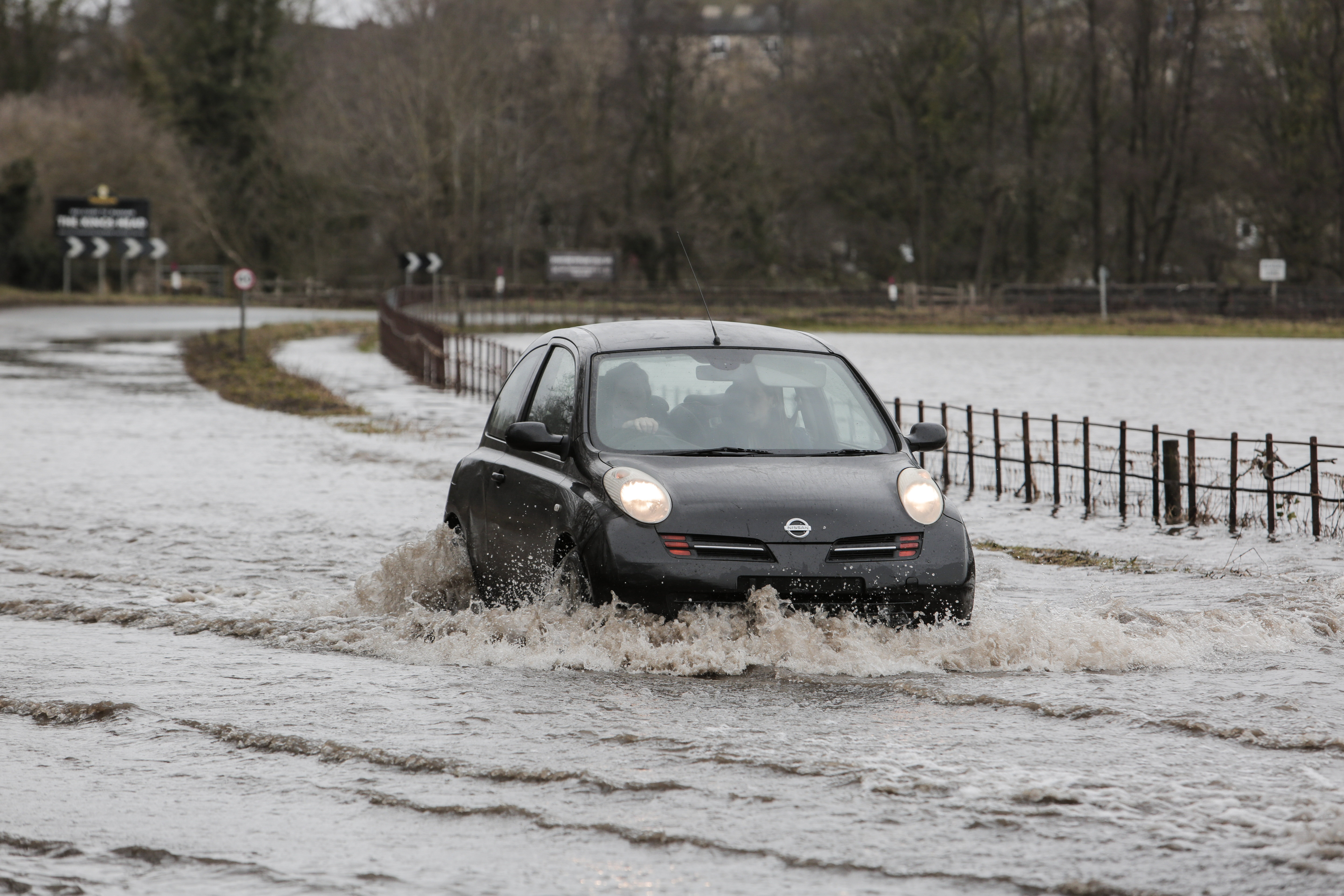A car driving through flood water on a road in Masham.