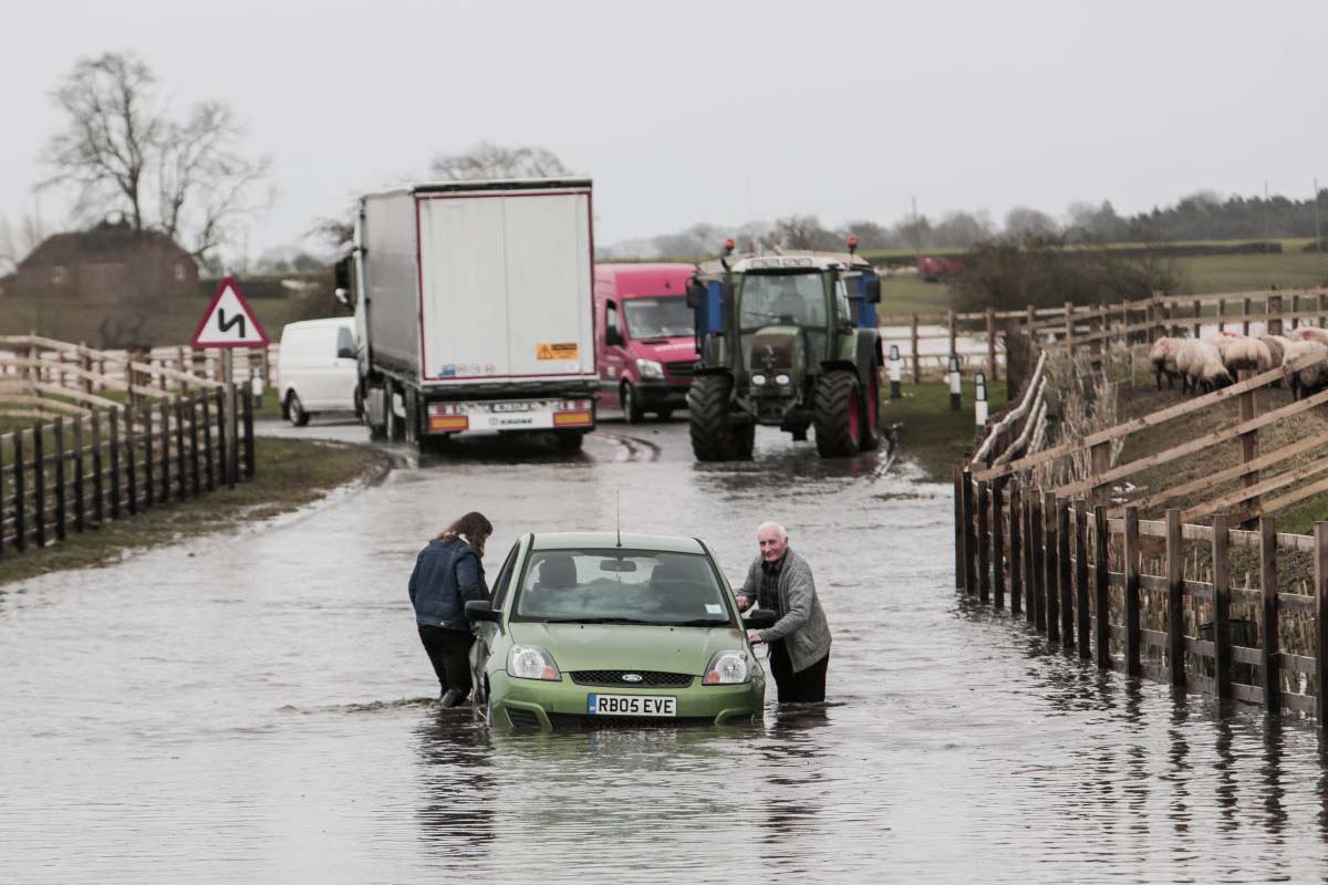Rescuers moving a car stuck in flood water