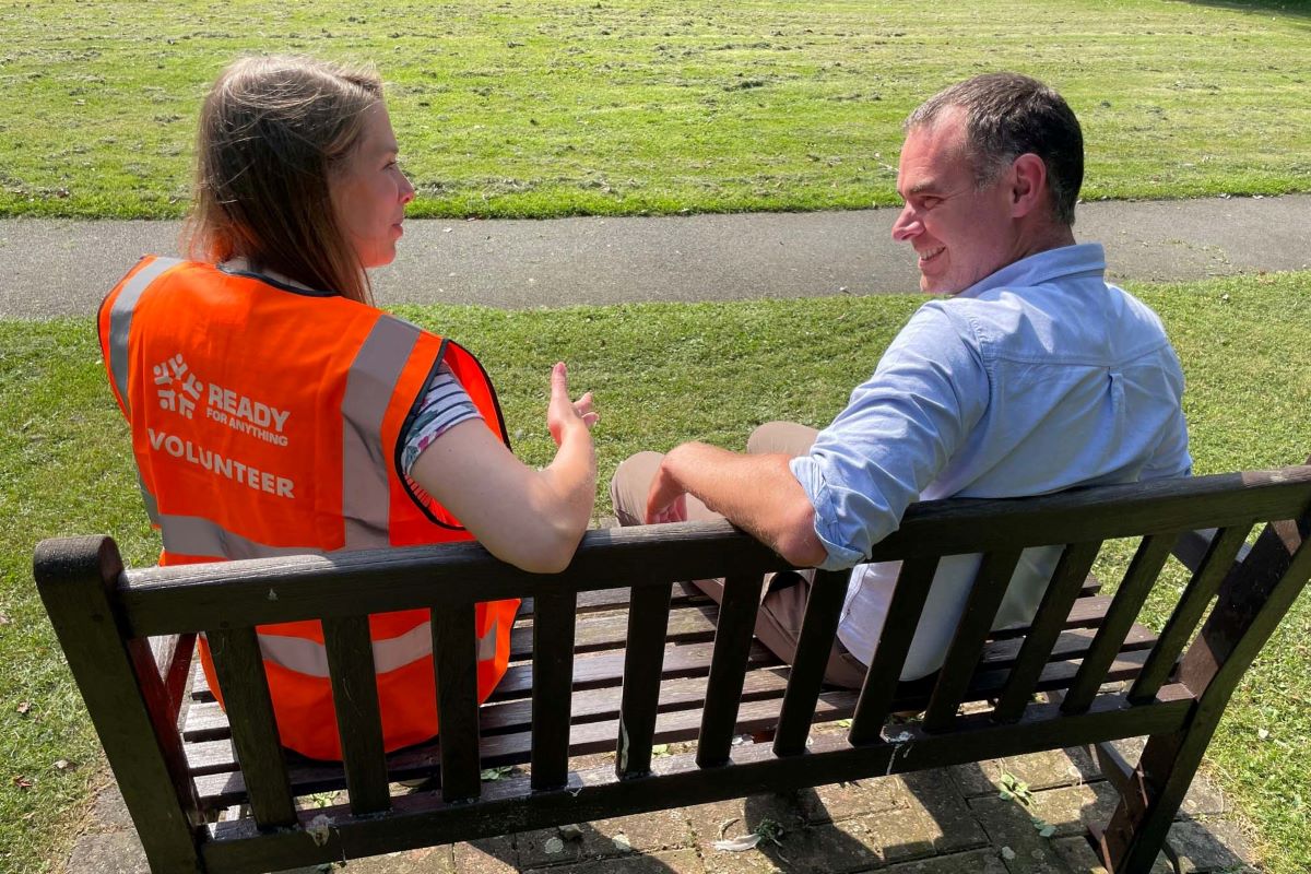 Two good neighbours talking together, seated on a bench.