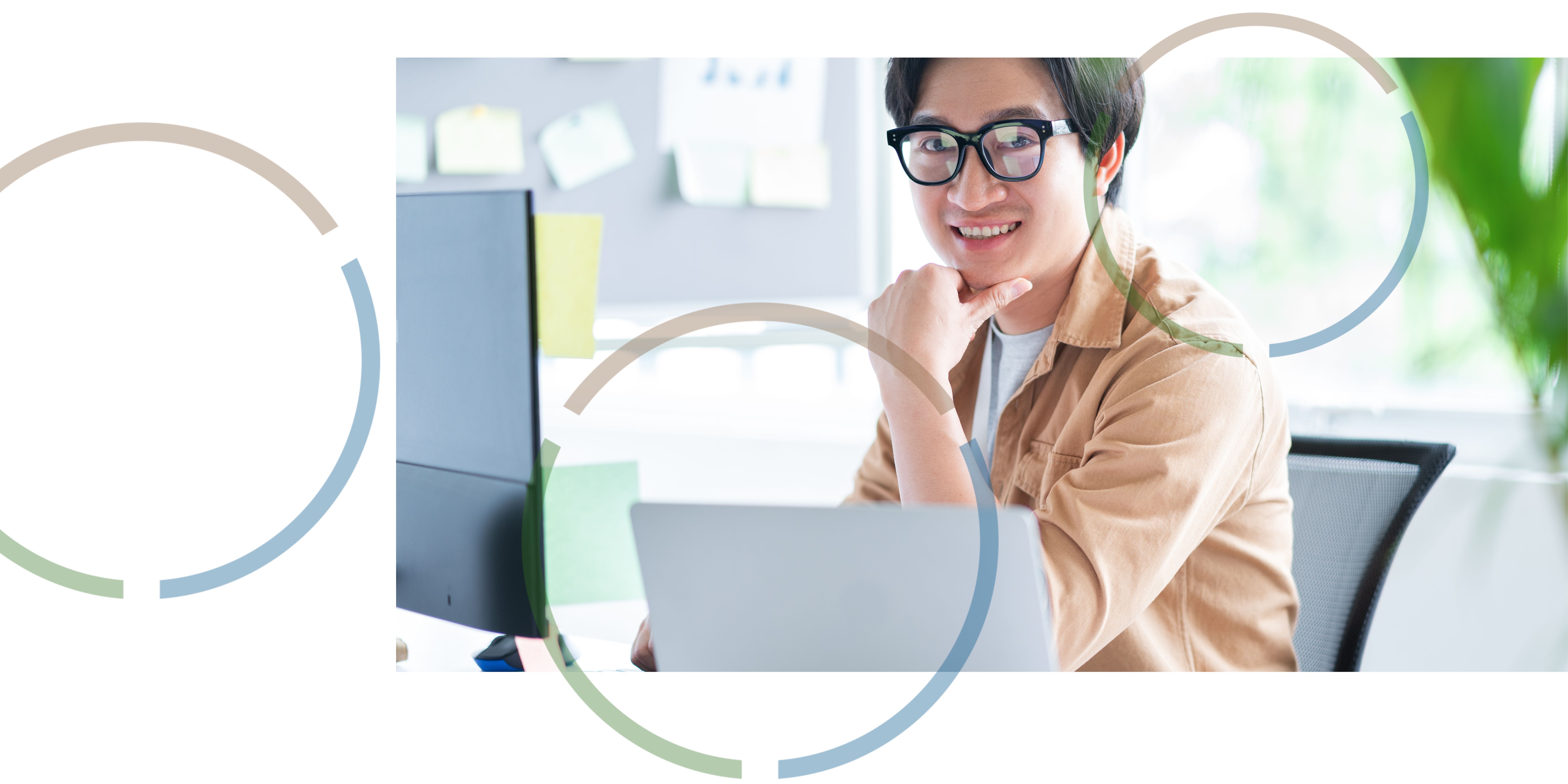 A man smiling and working at a computer.