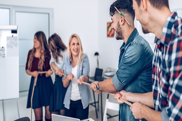 A group of people playing tug of war in an office.