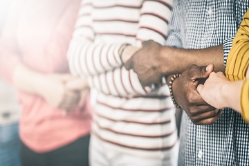 People standing in a row with their arms crossed and holding hands.