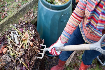 A person turning compost over with a gardening fork.