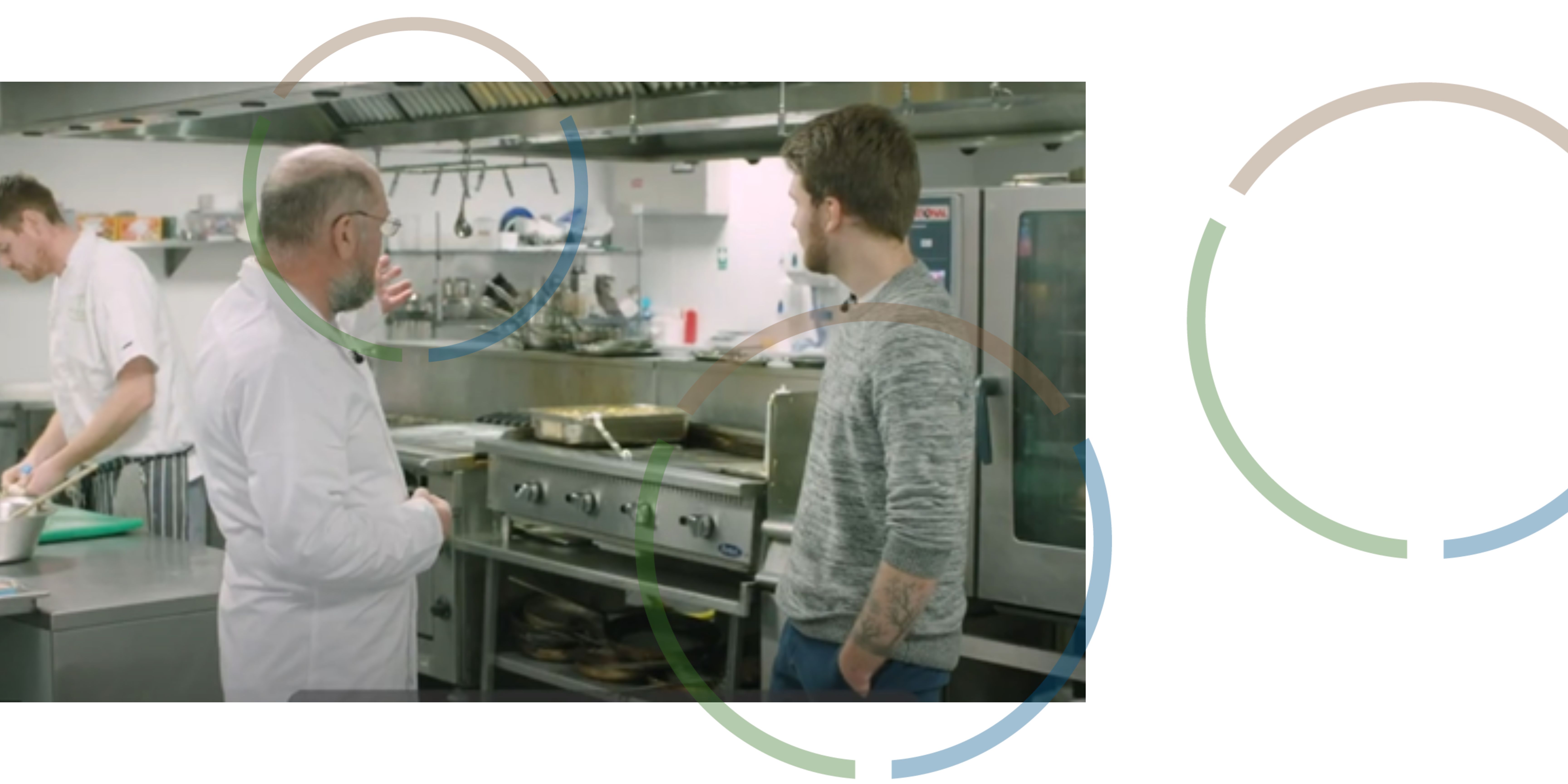 Three men talking and working in a large kitchen.