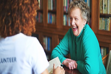 A volunteer and a woman talking and laughing in a library.