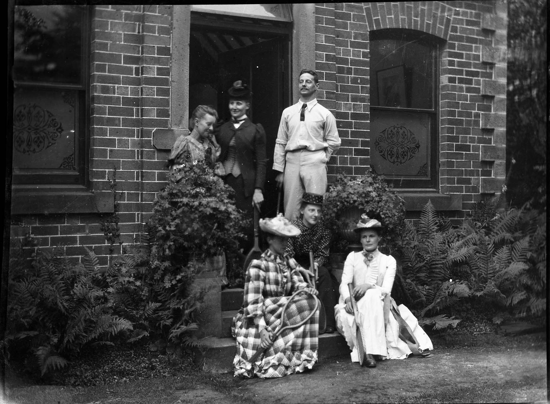 A family poses on their front steps with rackets