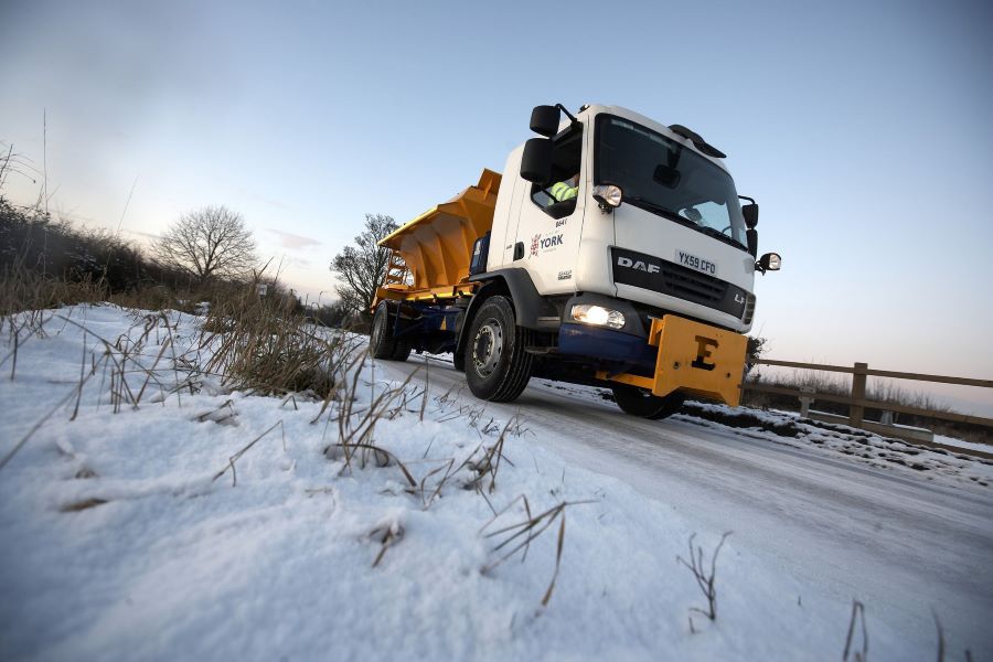 A gritter lorry driving through a snowy landscape