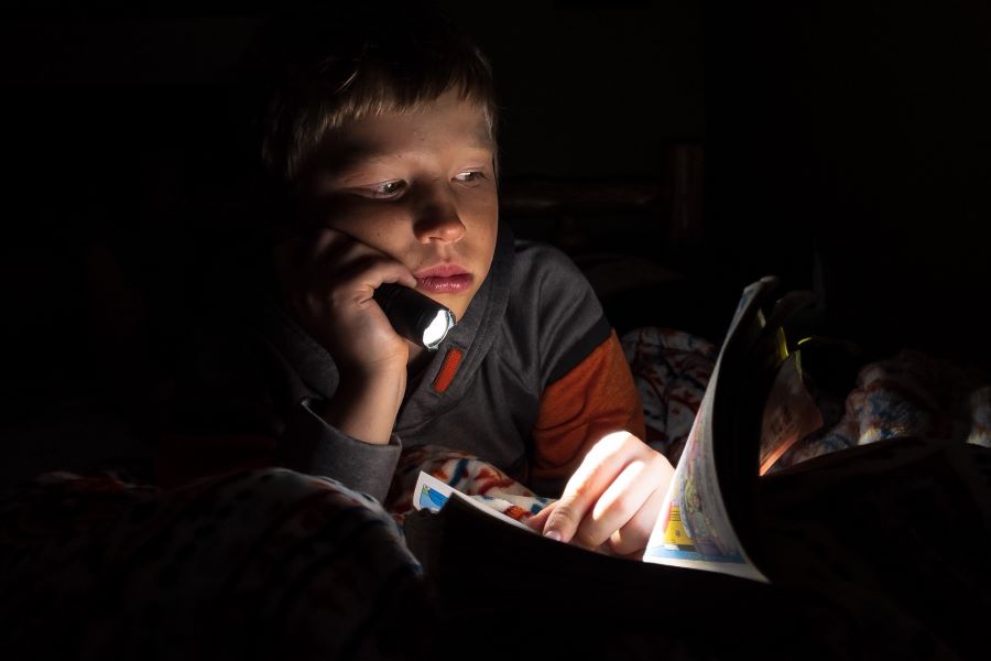 A boy reading by torchlight