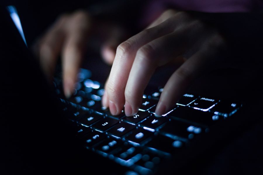 A close-up of fingers typing on a computer keyboard.