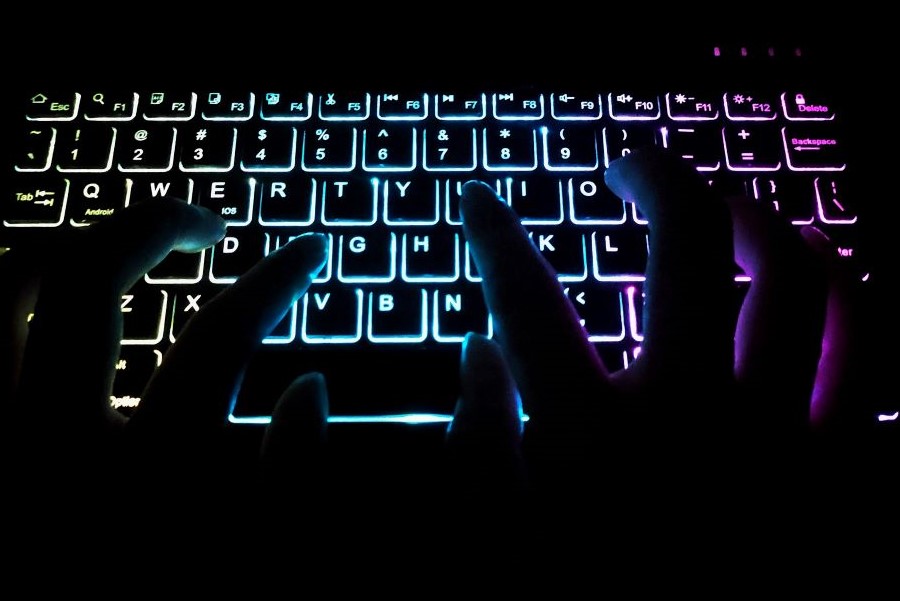 Fingers typing on a glowing computer keyboard