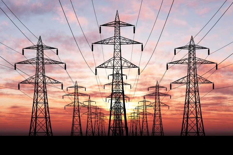 Pylons in a field against a red sunset