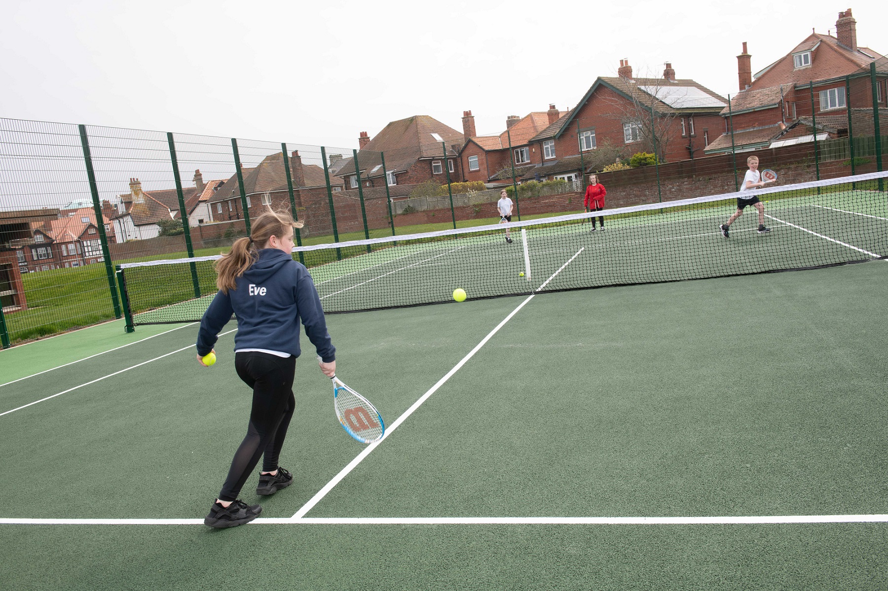 Children playing tennis outdoors.