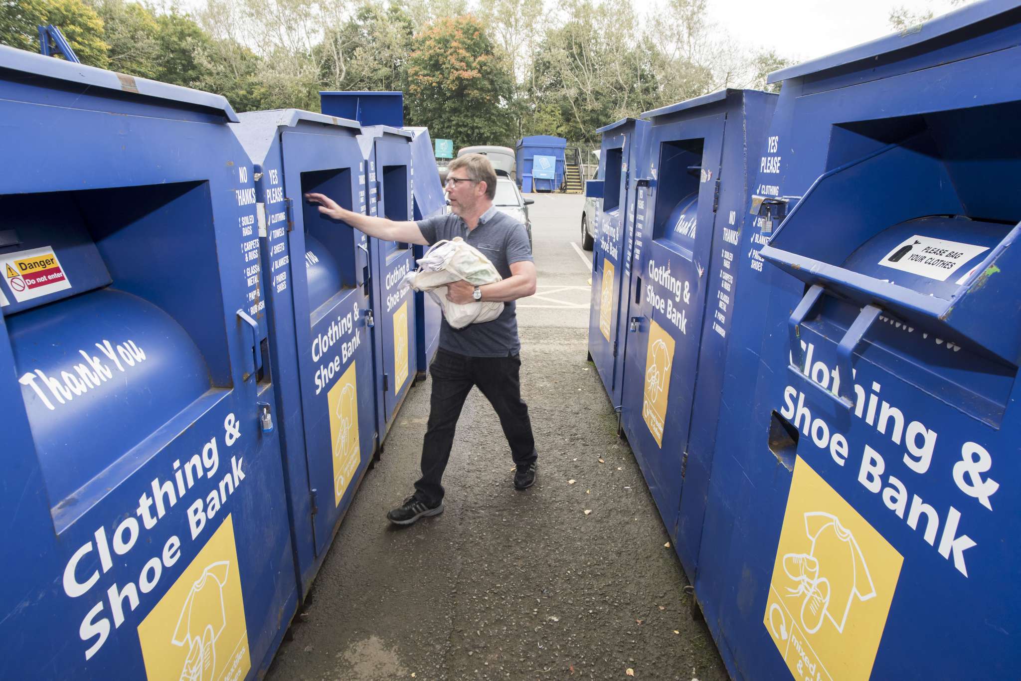 A man putting textiles in the recycling box