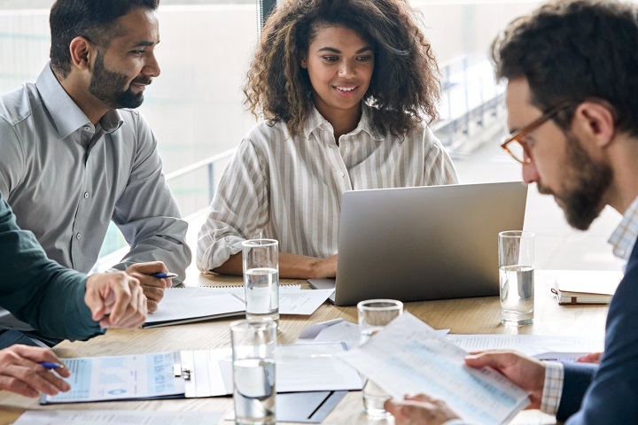 Three colleagues working in an office with a laptop