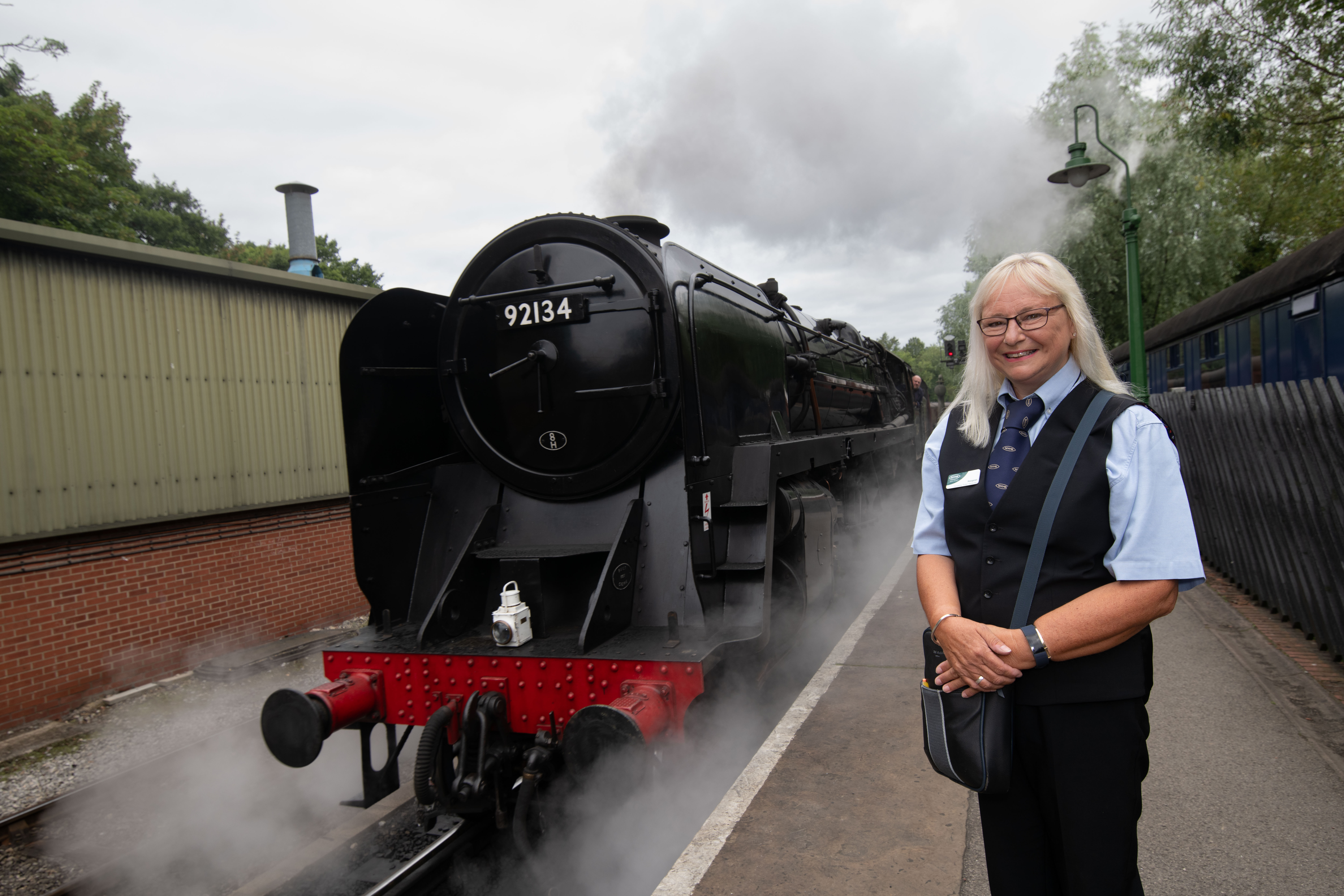 Volunteer Margaret Stainburn standing and smiling on the train station platform.