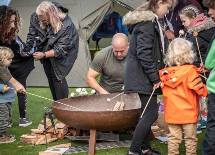 A family group around a fire pit toasting marshmallows