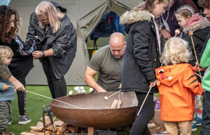 A family group around a fire pit toasting marshmallows