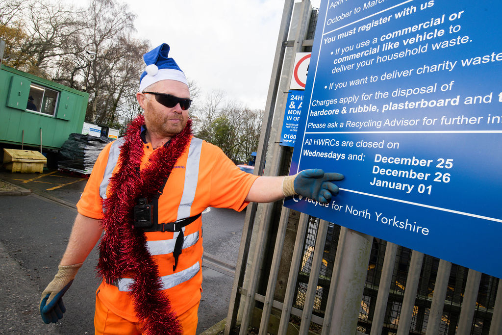 A HWRC worker pointing at the HWRC opening hours