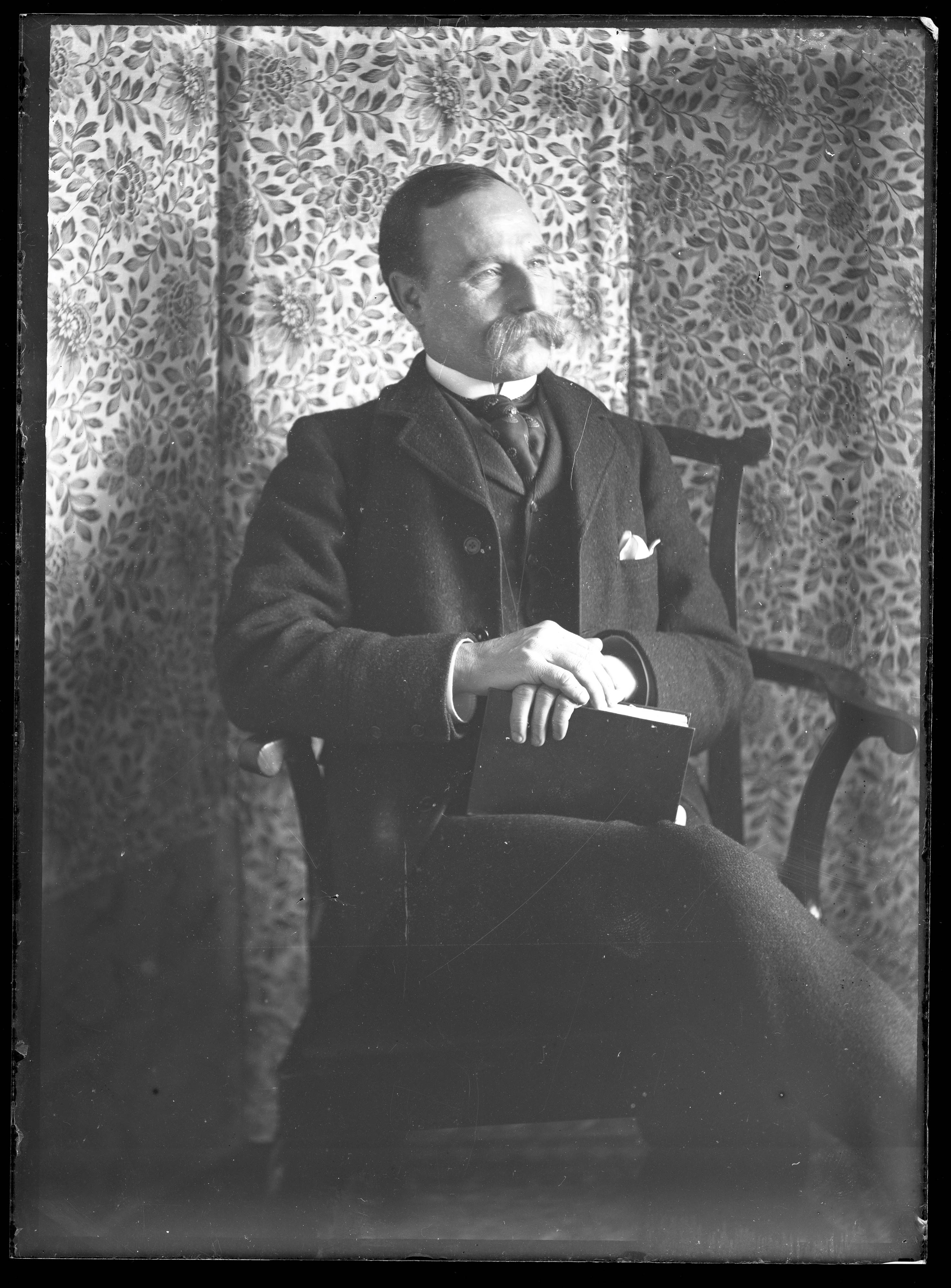 A man holding a book, as he poses for his photographic portrait. It was common practise to pose with items such as books for formal portraits. From a collection found at the former photographer’s shop, Cheapside, Knaresborough. The photo dates from the Edwardian era.
