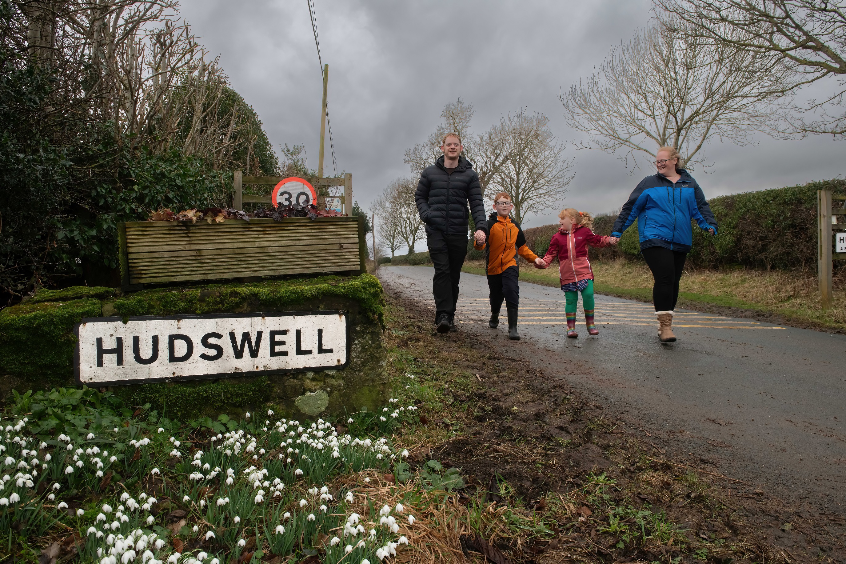 David and Caroline Harper, with their children, Phillip and Lucy walking past the sign for Hudswell