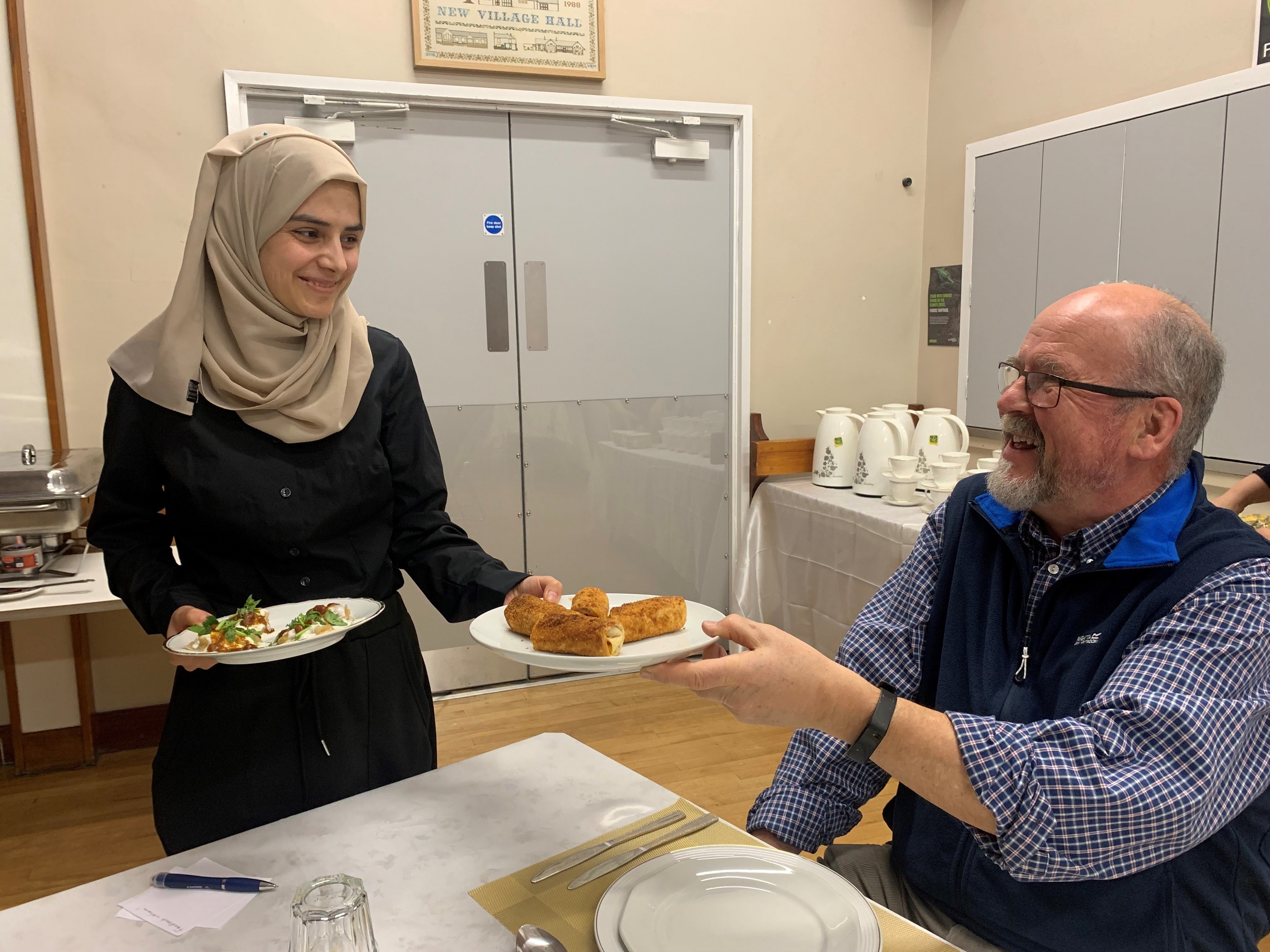 Sonia Omari serving home-made Afghan cuisine to ing ePeter Creek at the pop-up dinvent at Embsay Village Hall.