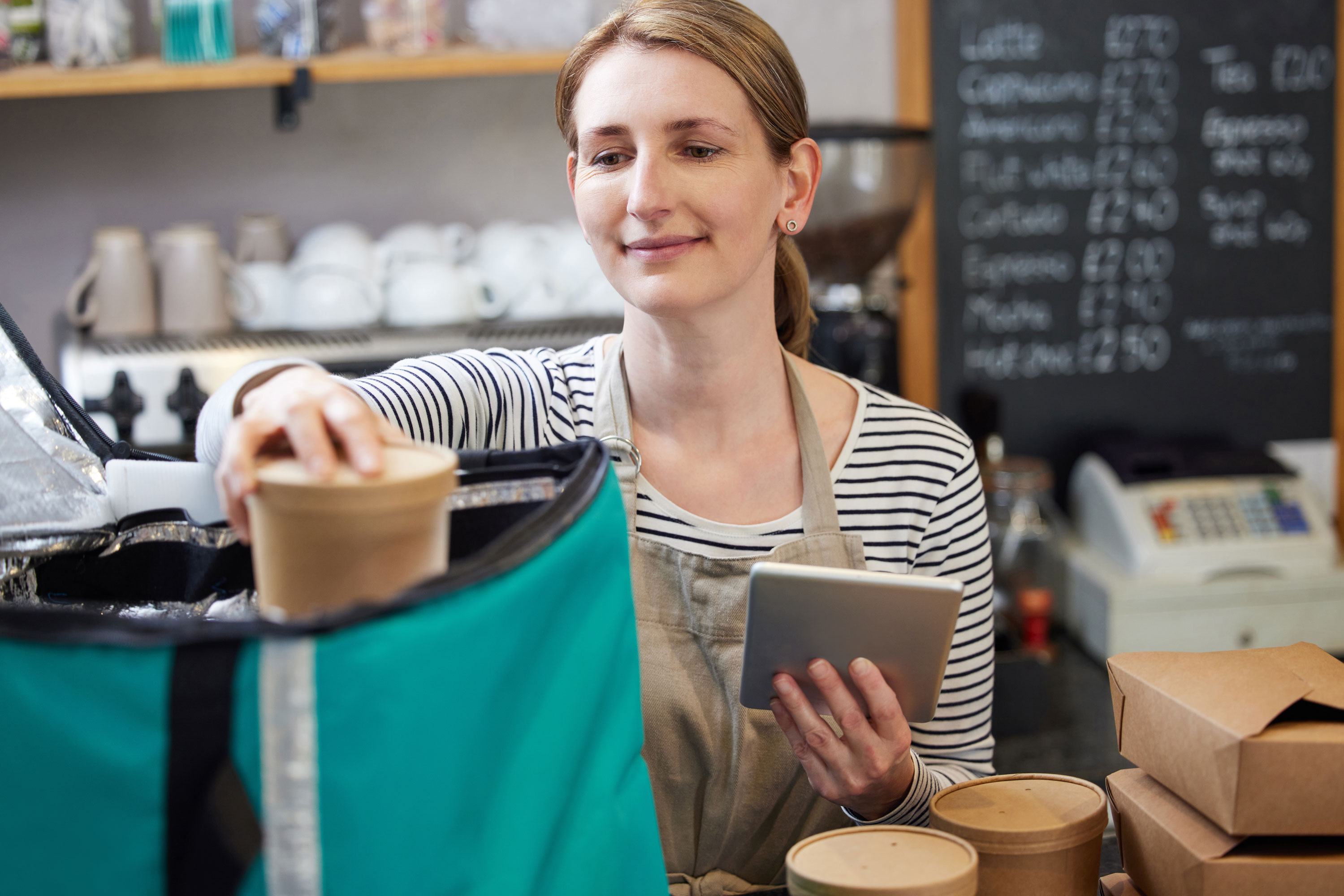 Woman preparing takeaway delivery using sustainable packaging