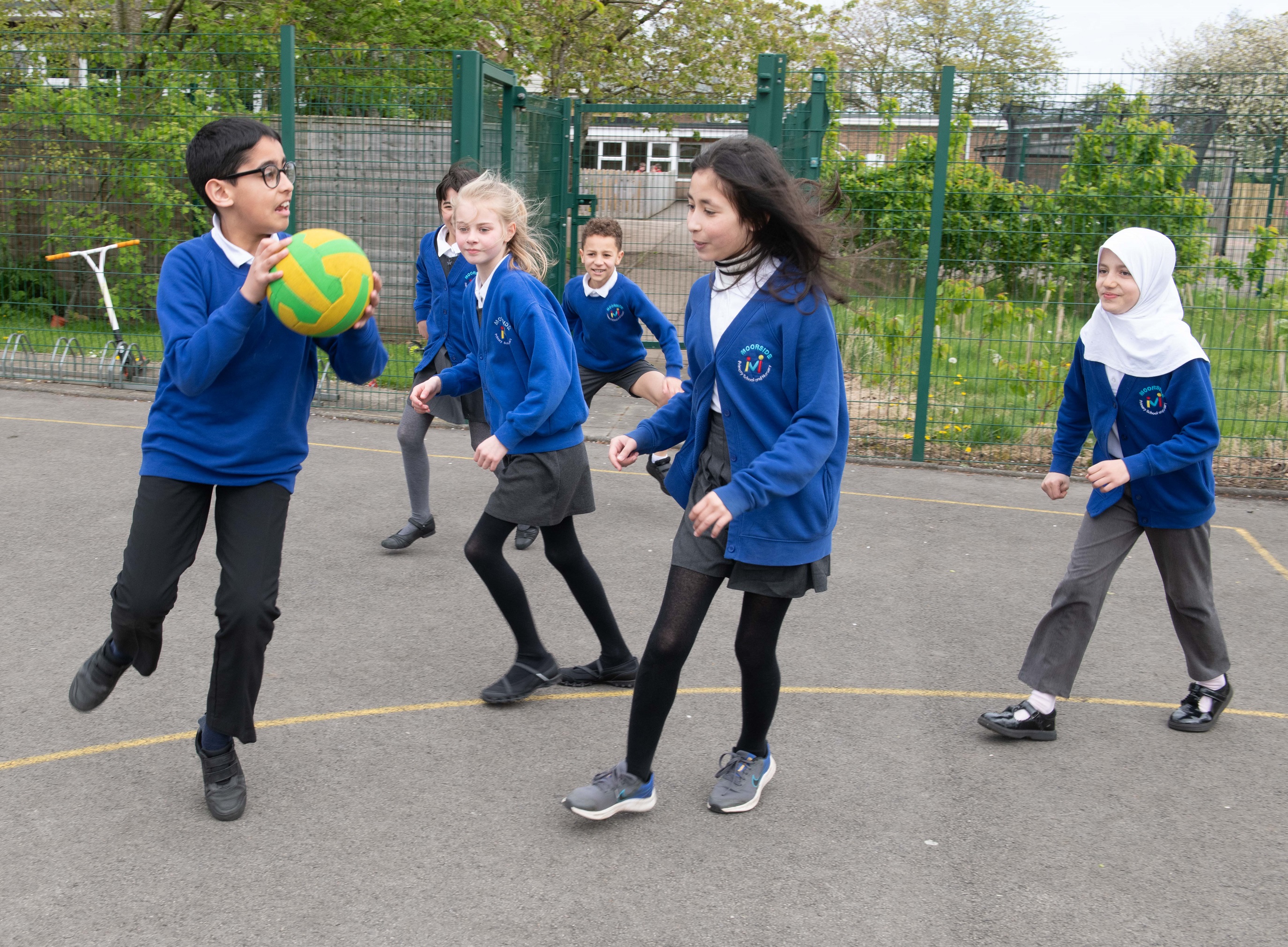 School children playing with a ball in a play ground