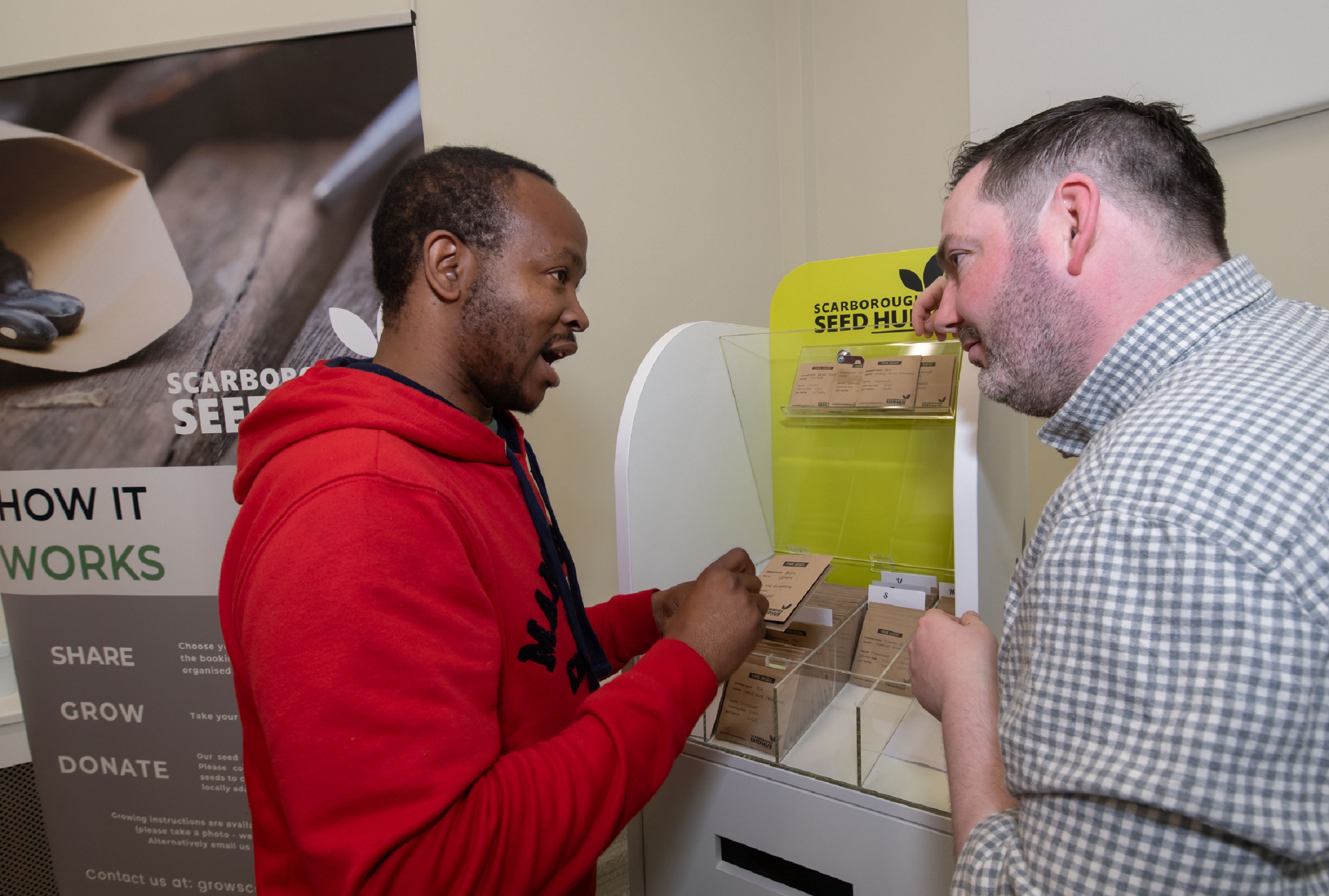Darren Mancrief, founder and co-chairman of GROW Scarborough, explaining how the seed hub works with library visitor Athenkosi Nyengane