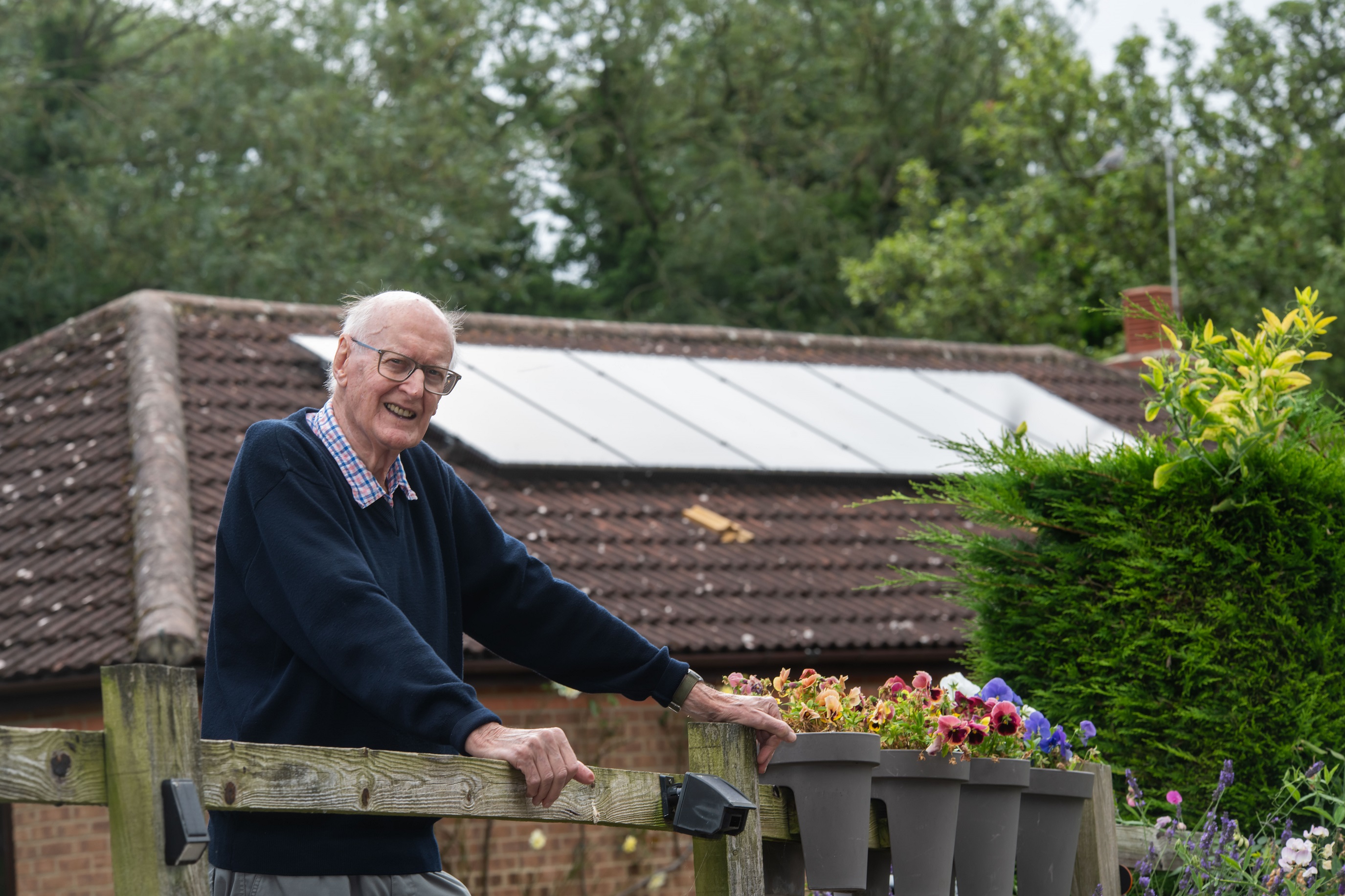 Geoffrey Evans in front of a house with solar panels