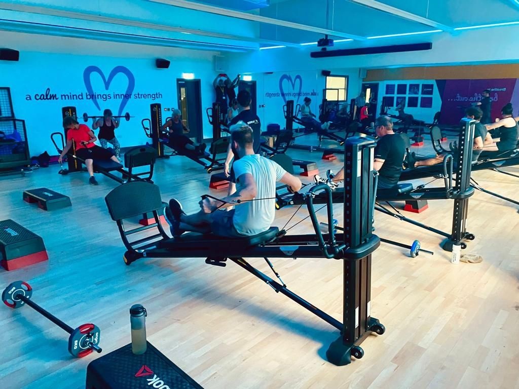 A group using Harrogate Leisure and Wellbeing Hub's gym facilities including people on rowing machines and lifting weights
