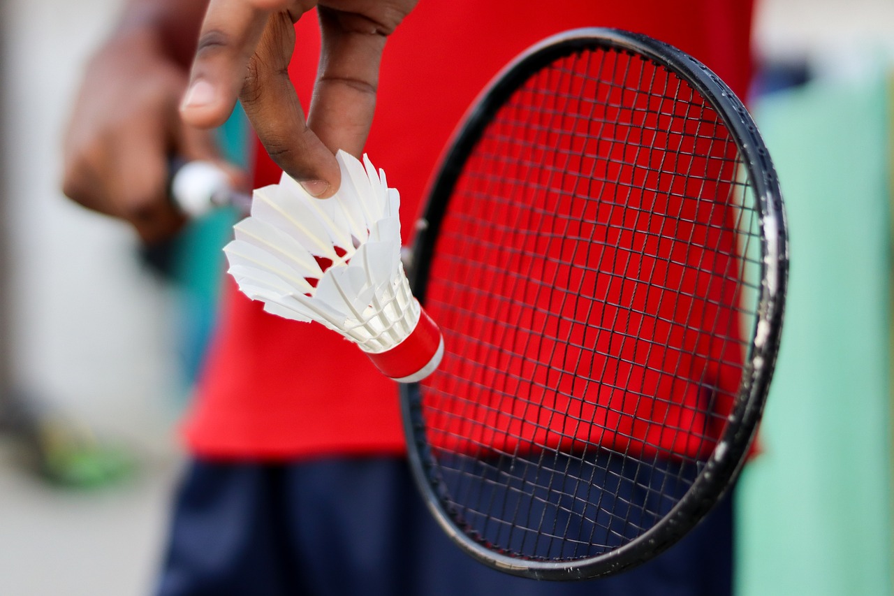 Someone holding a shuttlecock and badminton racquet, ready to serve