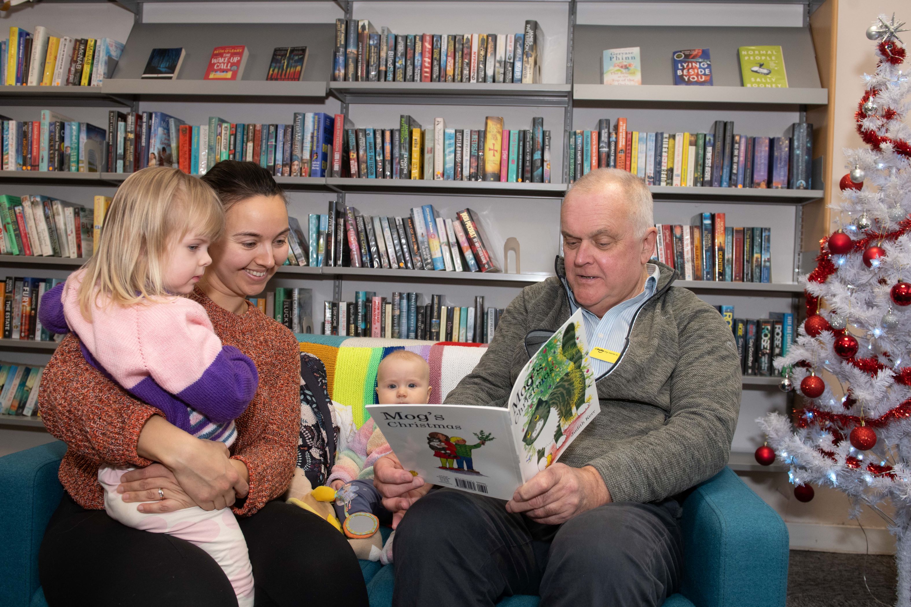 Two adults and a child reading in a library