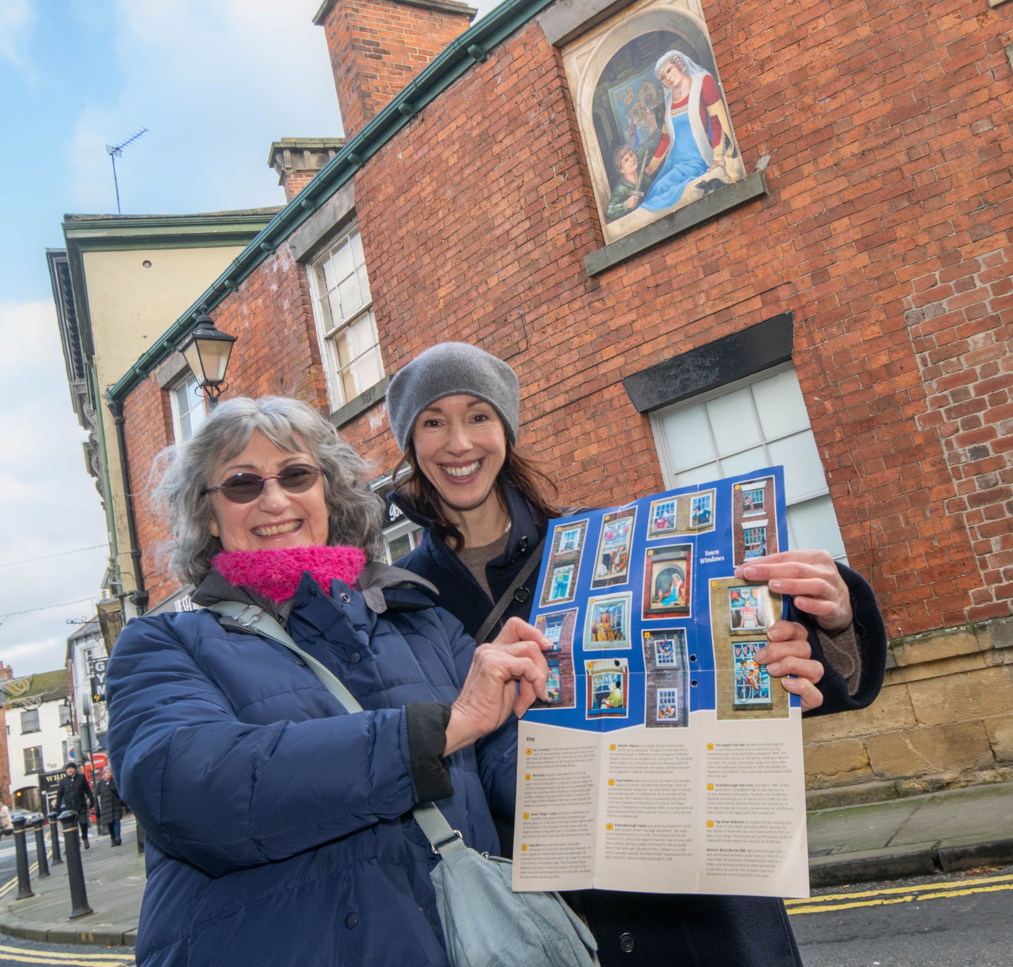 Cllr Hannah Gostlow who represents the Knaresborough east division with the chair of Knaresborough Renaissance at the window trail with picture of Queen Philippa by Ray Mutimer in window behind them.