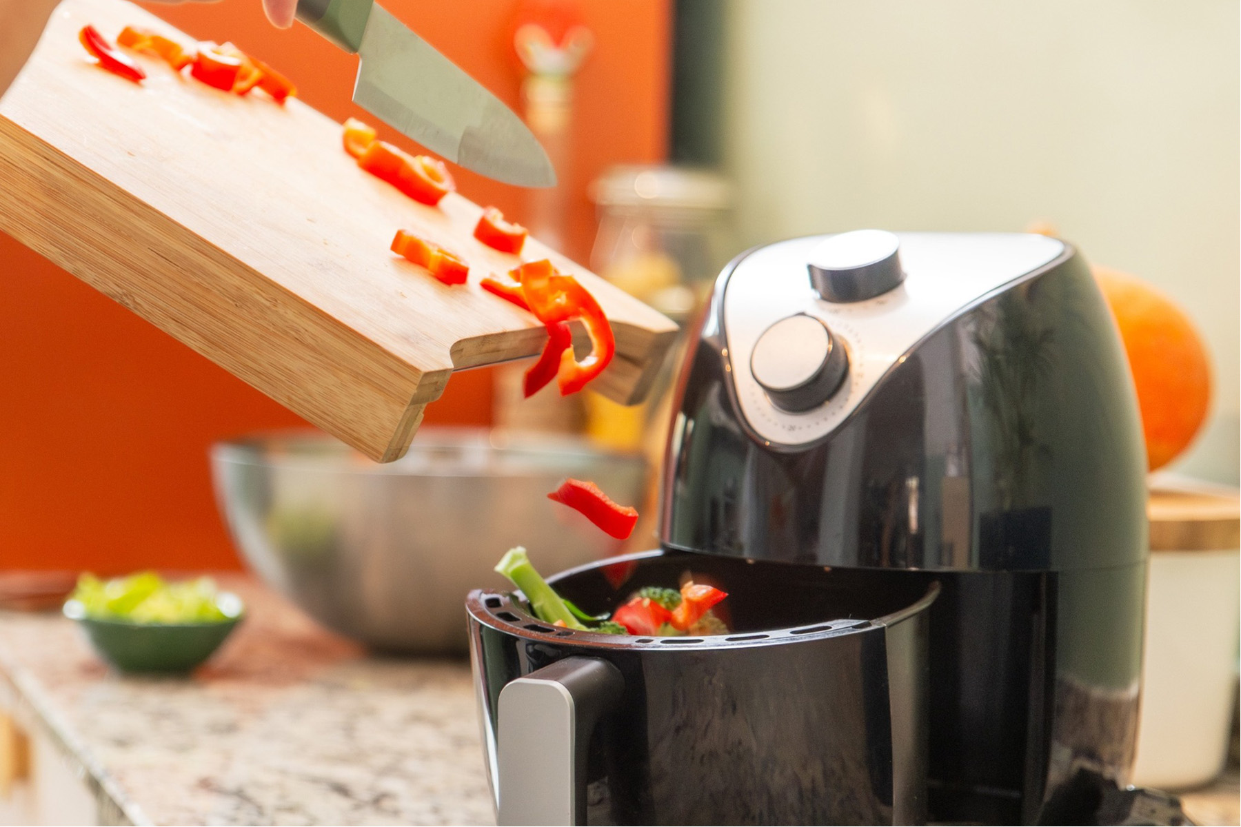 Chopped peppers being poured into an air fryer