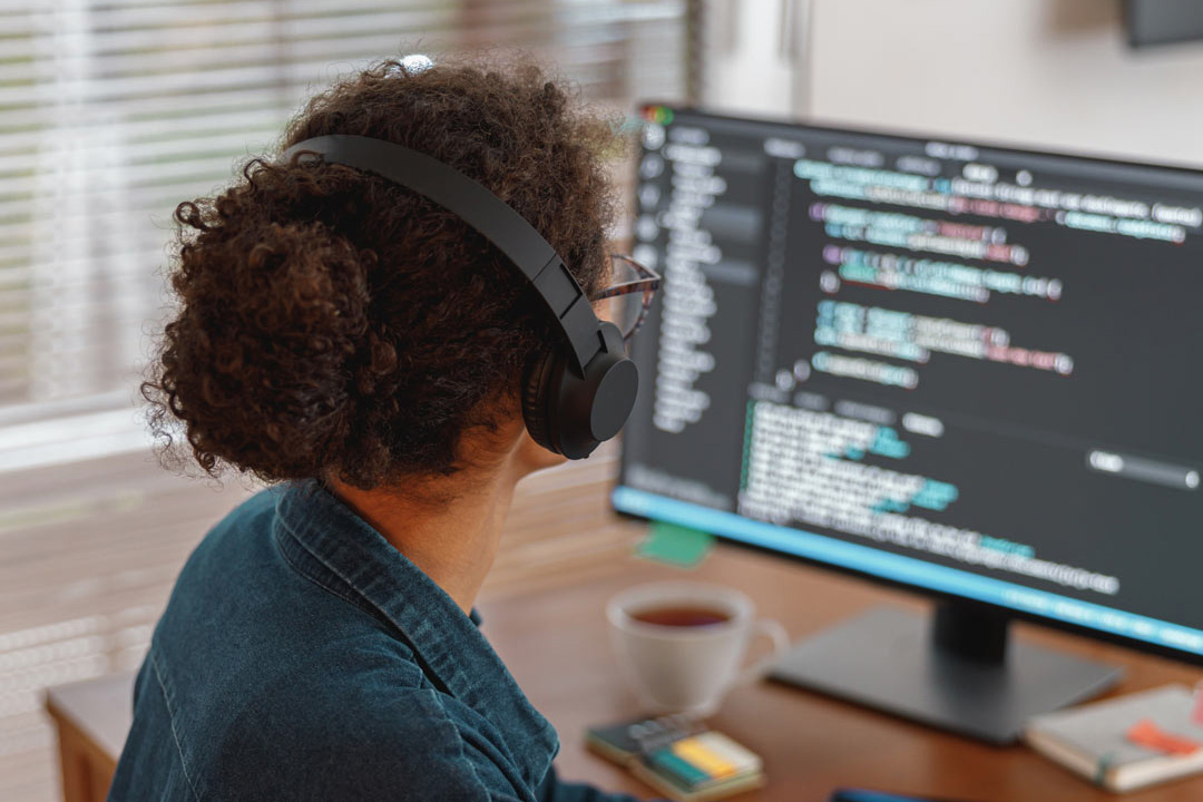 Woman wearing headphones using a programming software.